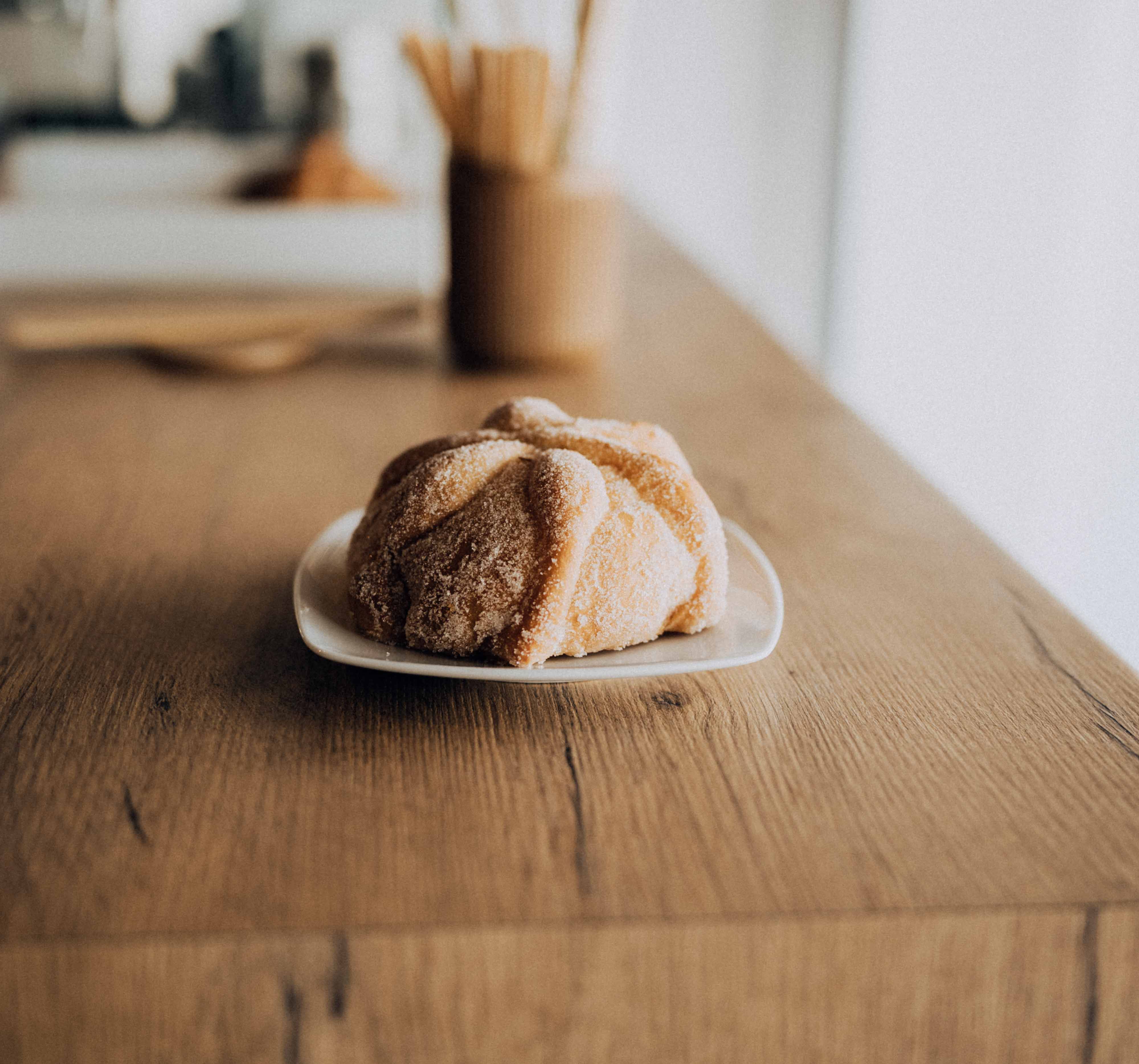 Pan de muerto en un plato sobre una mesa de madera