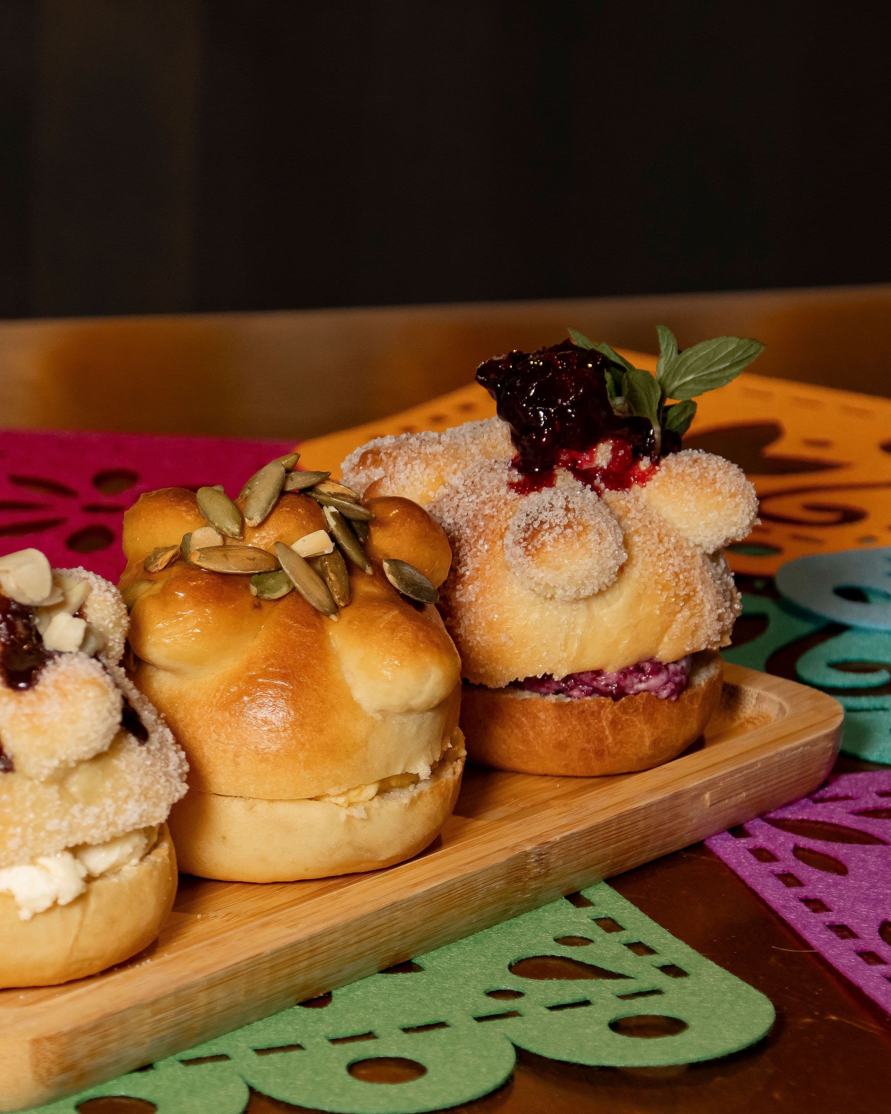 Panes de muerto rellenos con mermelada y pepitas sobre papel picado