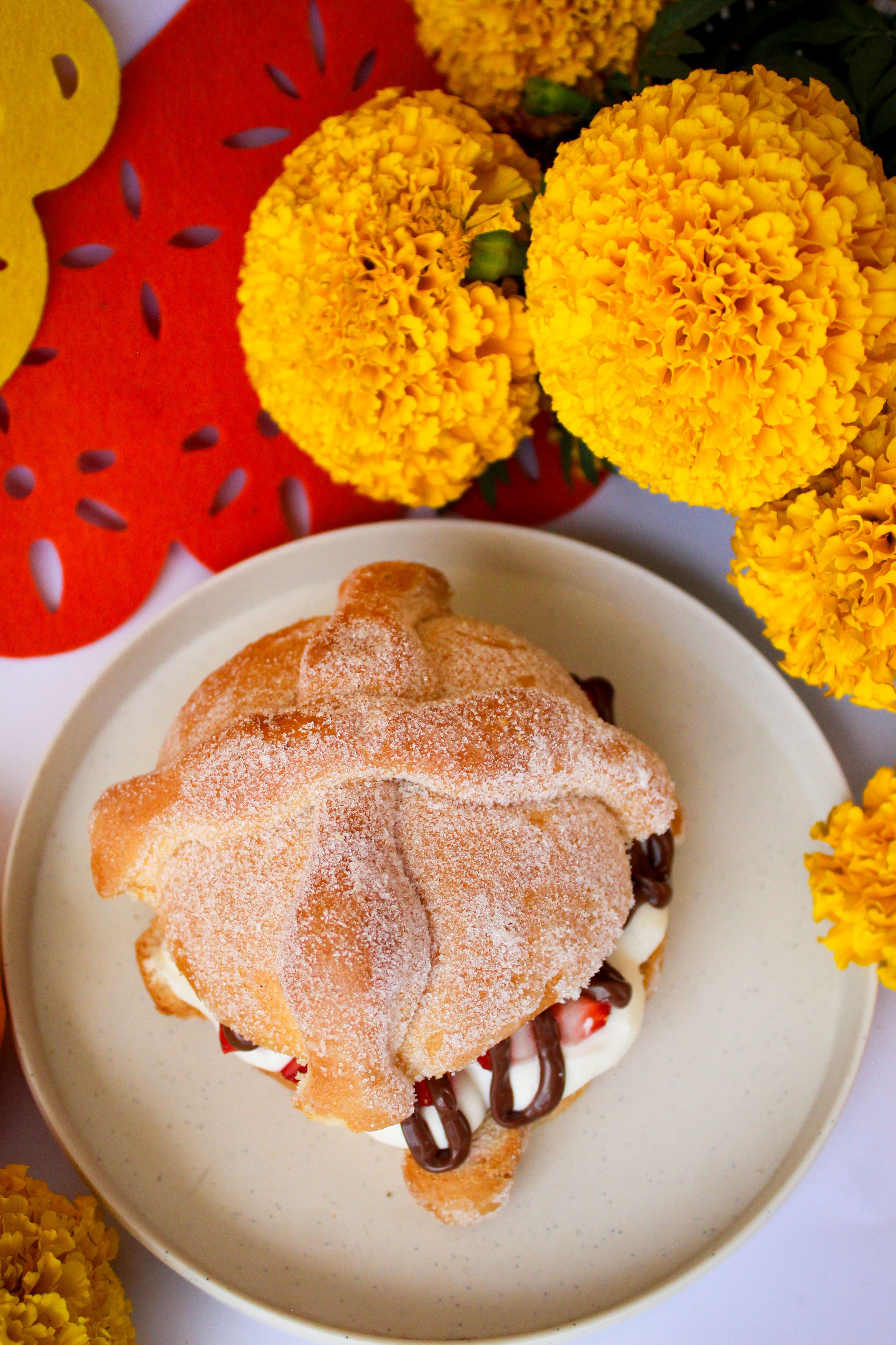 Pan de muerto relleno de chocolate y fresas entre flores de cempasúchil