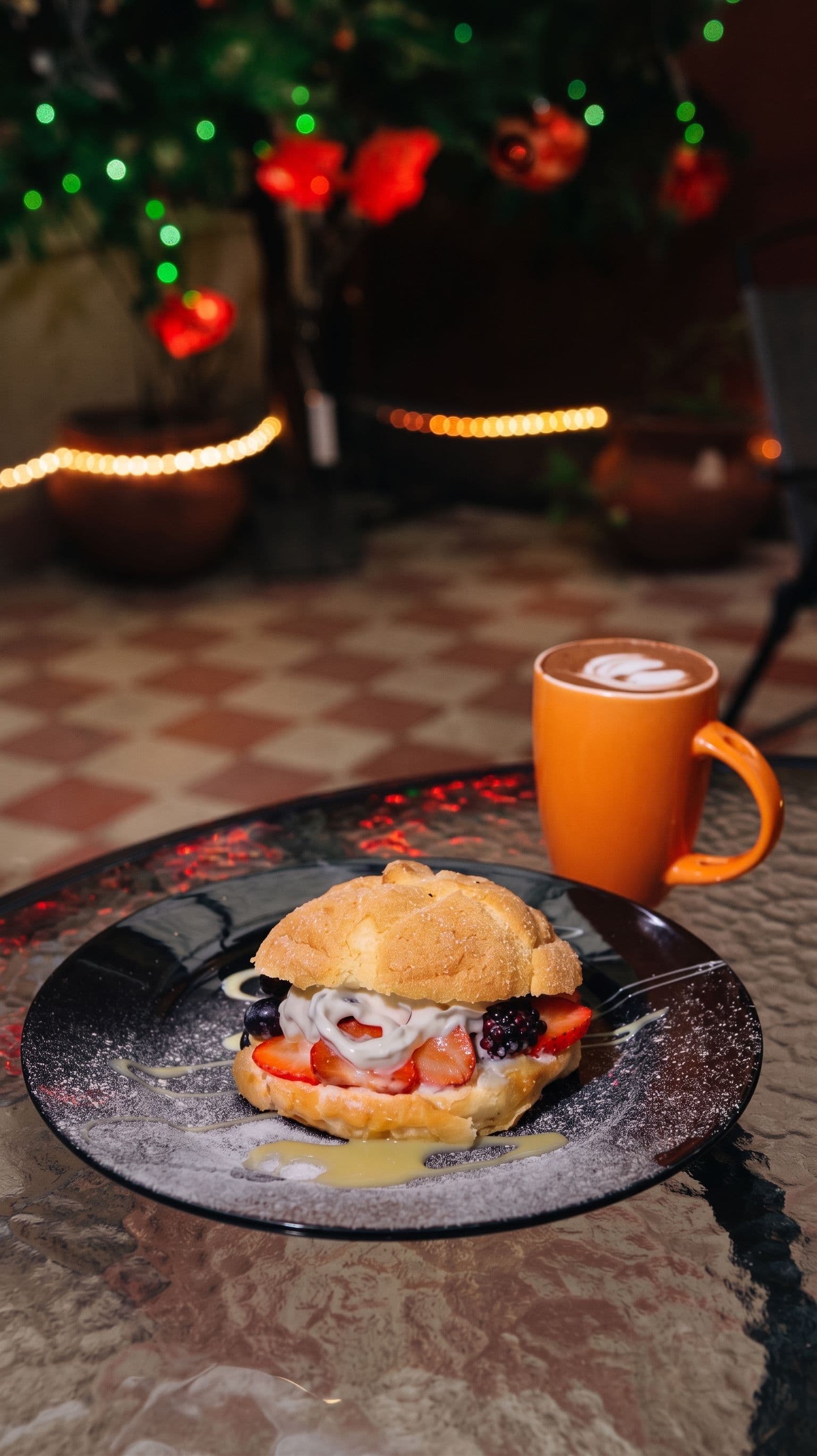 Pan de muerto relleno de fresas y crema junto a una taza de café